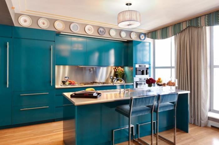perdažyta virtuvė, anties mėlyni baldai, dekoratyviniai indai viršutinėje sienos dalyje, prie lubų, būgno šviesa iš pusiau permatomo dramblio kaulo audinio