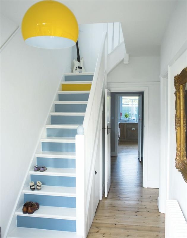 Gera idėja, kaip apšviesti baltą prieškambarį mėlynais laiptais ir geltonais akcentais, barokiniu veidrodžiu, apvalia geltona liustra
