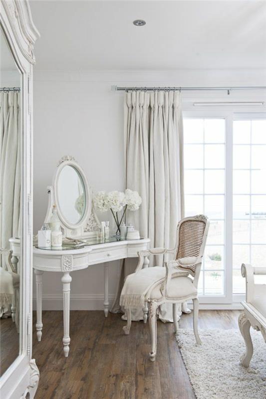 1 gražus „ikea“ tualetinis staliukas baltame medyje su dideliu langu, tamsios medinės grindys ir apvalus veidrodis-baltos užuolaidos
