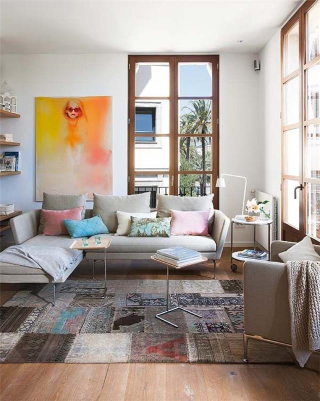 1 gauruotas spalvos kilimas svetainėje su gana pilka sofa ir dideliais langais