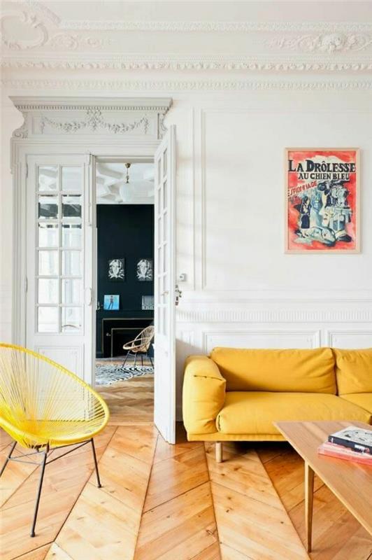 2 dekoratyviniai lipdiniai su karnizo lubomis-geltona oda-sofa ir geltona rotango kėdė-šviesios parketo grindys