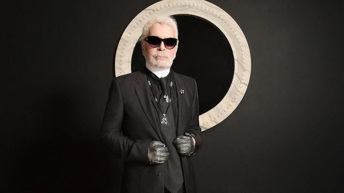 tasarımcı Chanel Karl Lagerfeld'in siyah takım elbisesi içinde at kuyruğu ve siyah bir arka plan üzerinde siyah gözlüklü fotoğrafı