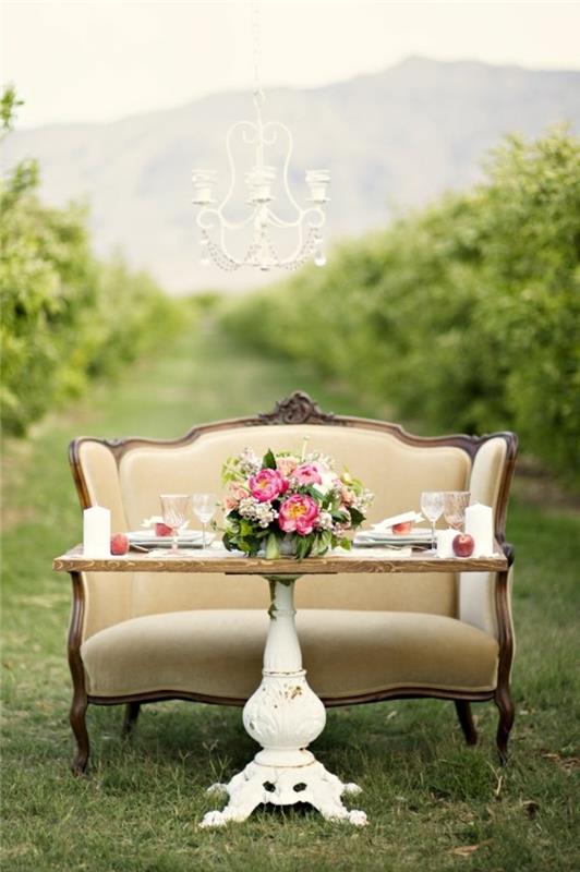 Idea per apparecchiare la tavola, tavolo in legno da giardino con un centrotavola vaso con fiori