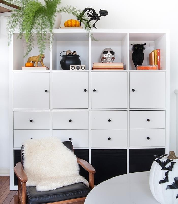 beyaz ve siyah ev cadılar bayramı dekoru, ahşap zeminli ve ahşap mobilyalı beyaz duvarlı oda, siyah kağıt yarasalı beyaz balkabağı