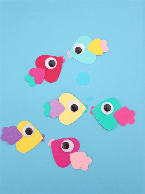 Mavi arka planda hareketli gözleri olan balıklar oluşturmak için birbirine yapıştırılmış kağıt kalpler ile orijinal yaz manuel aktivite fikri
