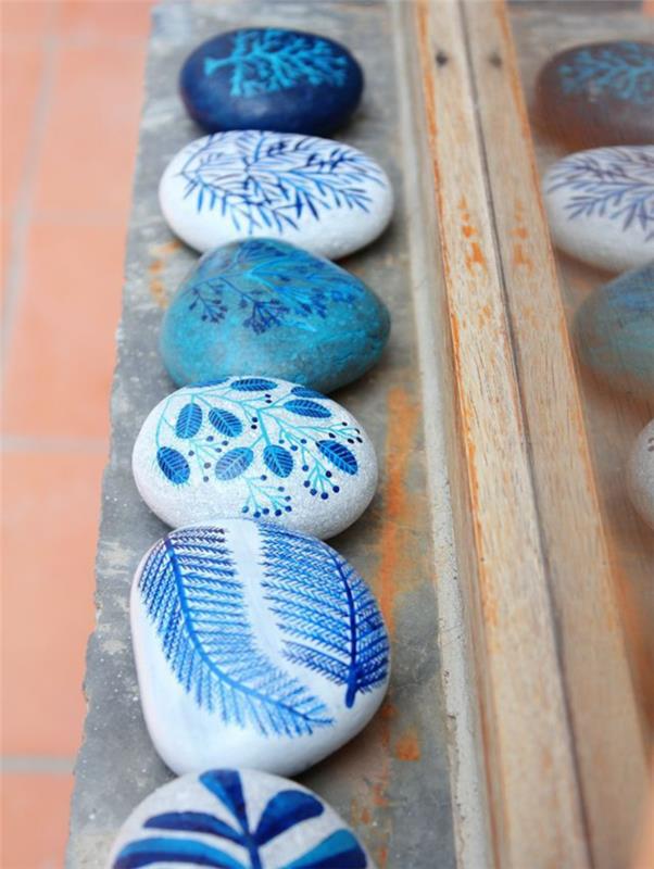 lepa dekorativna ideja s kamenčki, naslikanimi z rastlinskimi vzorci v modrih odtenkih