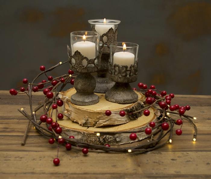 senovinė šventės puošmena, mediniai rąstai, raudonos uogos, senos žvakių poros ir uždegtos žvakės, papuošimas raudonomis uogomis