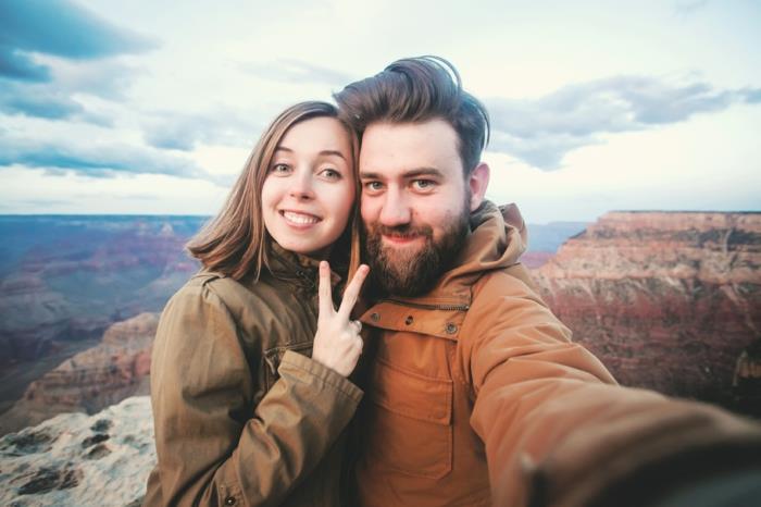 Romantik çift veya arkadaşlar, Arizona, ABD'deki Grand Canyon bakış açısında seyahat yürüyüşlerinde başparmaklarını gösterir ve selfie fotoğrafı çekerler
