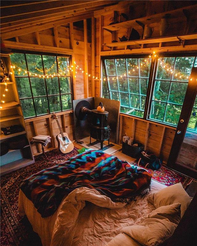Notranjost lesene brunarice, lahka girlanda, velika postelja z odejo dekorja v hipi elegantni gorski hiši, kul ideja, kako okrasiti prijetno spalnico