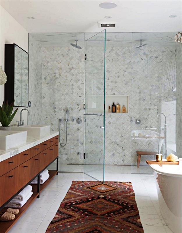 bela in lesena kopalnica z italijansko prho v majhnih ploščicah, položenih diagonalno, etnična grafična preproga, ki se ujema s starinsko toaletno enoto