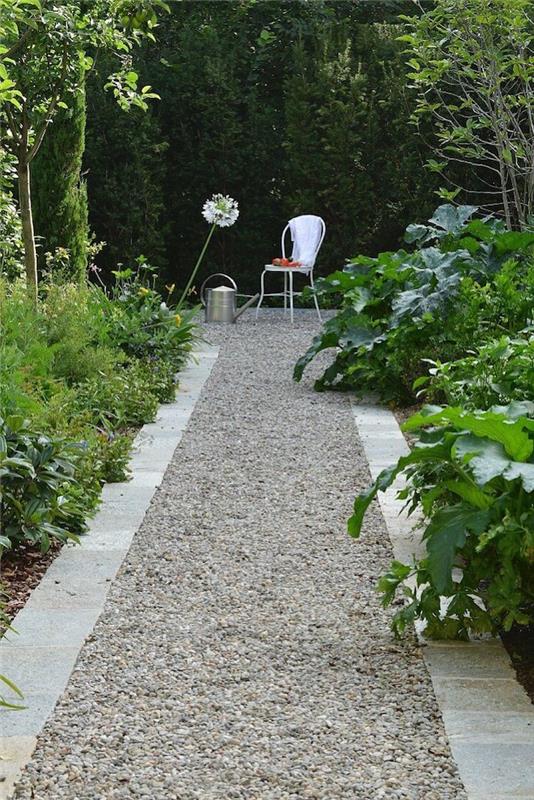 modernus sodo takas žvyruoto akmens apvaduose ribojasi su krūmais ir žaliais augalais