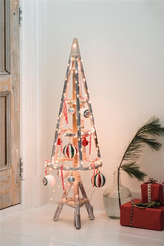 klasik Noel ağacına orijinal bir alternatif, beyaz, kırmızı ve yeşil geleneksel Noel süspansiyonları ve led ışık çelengi ile süslenmiş tripod tabanlı rustik ve eski ahşap bir Noel ağacı