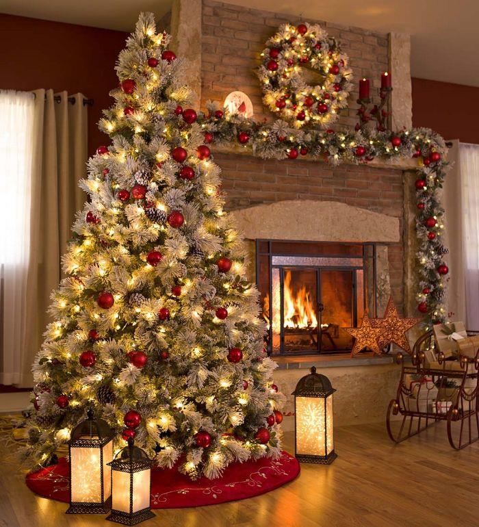 prijetno vzdušje božično drevo, okrašeno z zelenimi in belimi vejami ter rdečimi božičnimi kroglicami in lučkami v bližini okrašenega božičnega kamina
