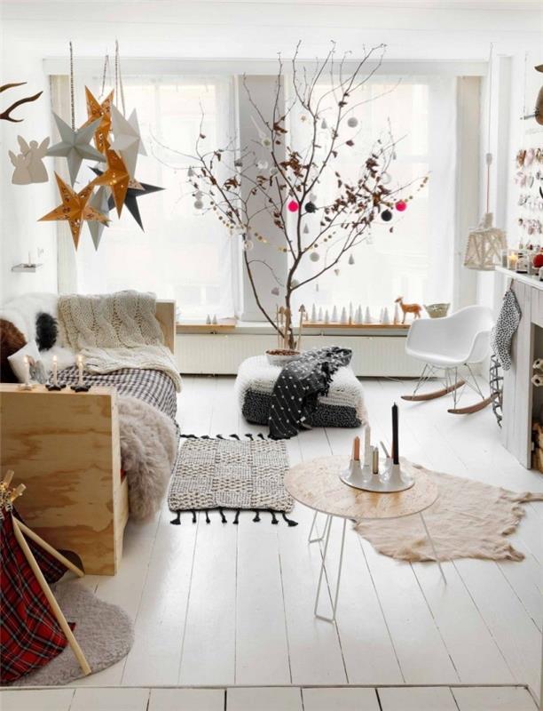 „cocooning deco“ baltame skandinaviško stiliaus gyvenamajame kambaryje, kuriame teikiamos pirmenybės minkštoms ir šiltoms medžiagoms bei tekstilės gaminiams, su gražia eglute, papuošta natūraliu interjero prisilietimu