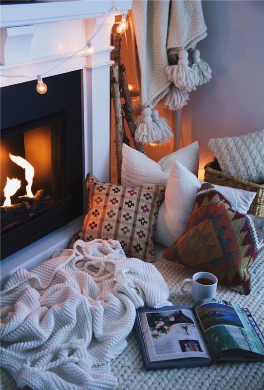 žiemos dekoras, „hygge cocooning“ atmosfera, dideli tinkliniai kilimėliai, minkšta antklodė, lengva girlianda, romantiškas židinys, dekoratyvinės pagalvėlės