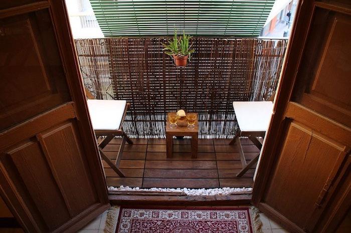 mažos balkono apdailos idėja ant medinių grindų su mini stalu ir kėdėmis
