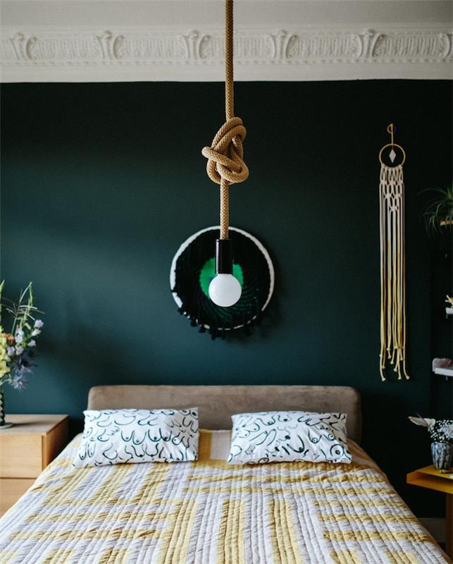 zamisel o naftno modri barvi, ki teži k zeleni, ohišje žarnice in vrvi, siva postelja z belo in rumeno posteljnino, lesena nočna omarica, majhen lovilec sanj