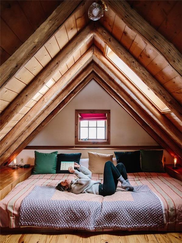 įrengti miegamąjį po stogu, sienas ir lubas medinėmis lentomis ir atviromis medinėmis sijomis, jaukią lovą ant čiužinio ant grindų, vasarnamio dekorą