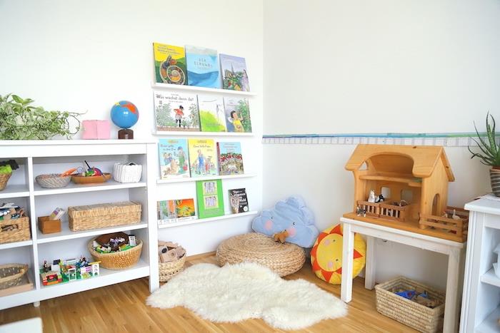 montessori namuose, montessori veiklos kampelis su osmanais, vaikiškos pagalvėlės, balta žema lentyna, knygų lentynos