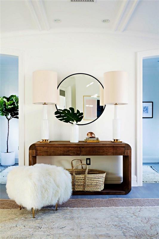 ideja moderne dekoracije doma, postavitev sodobnega vhoda z oblikovano leseno konzolo, krznenim stolčkom in velikim okroglim ogledalom