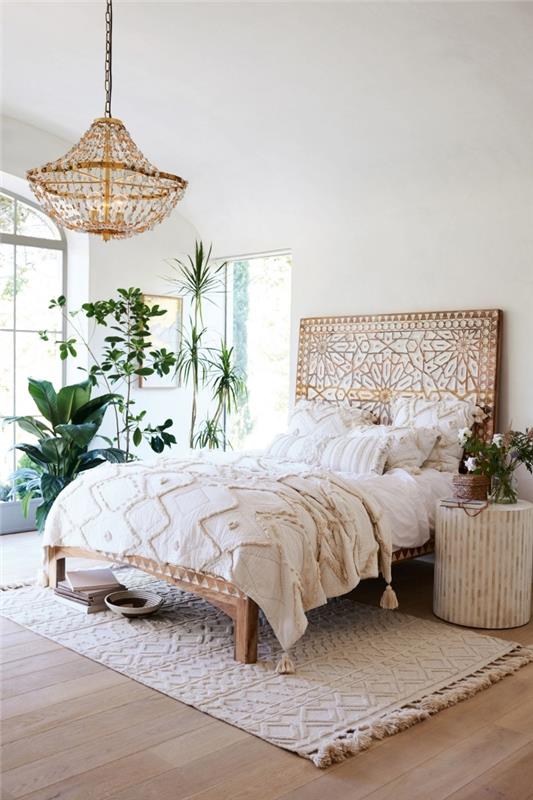 zasnova spalnice v boemskem slogu z belimi stenami s svetlim lesenim podom in lesenim vzglavjem v dizajnu mandala