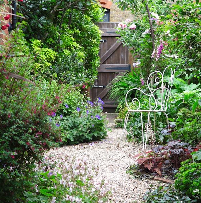 beli kamenčki, ideja, kako okrasiti svoj vrt, zeleni kotiček na dvorišču s temno rjavimi lesenimi vrati