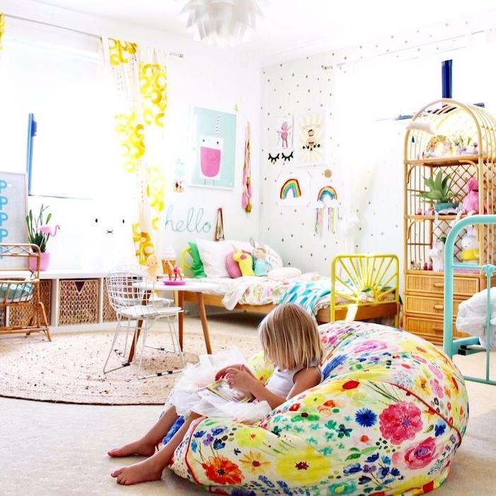 „Montessori“ miegamojo dekoro idėja su apvaliu jūros žolės kilimėliu, spalvinga lino lova, dideliu barbaru, sienomis, dekoruotomis vaikų piešiniais, pintais baldais vaikų kambariui