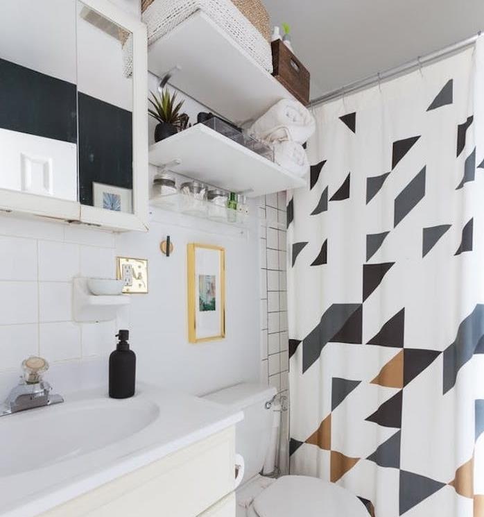 klozet üstü raflı küçük banyo, geometrik desenli duş perdesi, entegre aynalı dolap