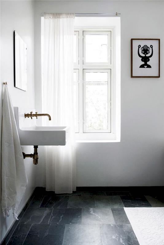 Švedska minimalistična kopalnica s starinskim kvadratnim umivalnikom in retro zlatim bakrenim vodovodom na tleh s ploščicami iz temnega marmorja in belimi stenami