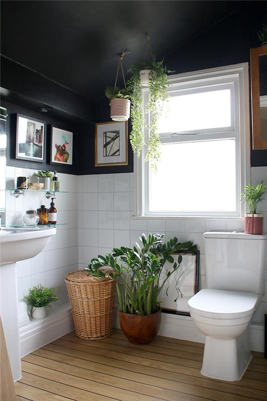 bohemiško prašmatnaus dekoro idėja mažame baltos ir juodos spalvos vonios kambaryje su medinėmis grindimis, idėja patalpų žaliems augalams ir mediniams aksesuarams
