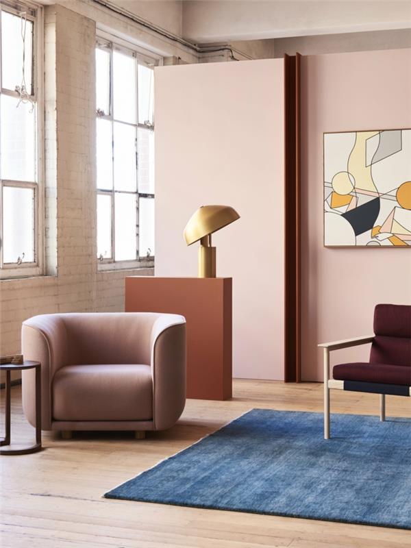 pastelno rožnati kavč, modra preproga, stol iz blaga in lesa, ženstvena zasnova dnevne sobe