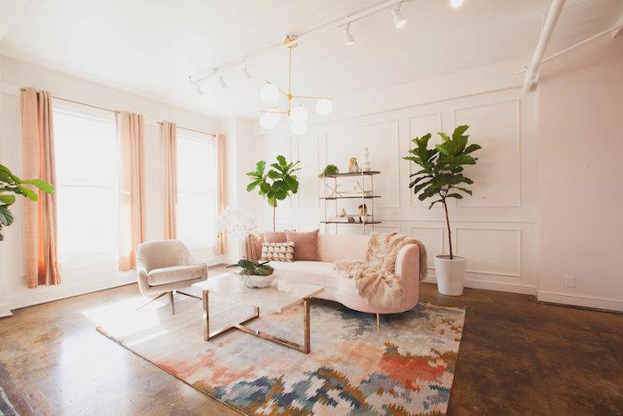 minimalističen dekor dnevne sobe z rožnatim kavčem, pisana preproga, naribna in kovinska miza, tla z rjavim učinkom, bele stene, dekor dnevne sobe