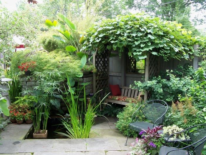 sodo išdėstymo idėja, poilsio zona su mediniu suoleliu su augaline arka, metalinės kėdės, akmens plokštės žemė, kelios žalios pėdos