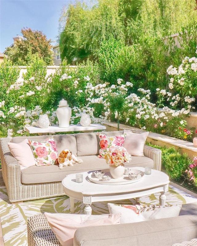 viršuje sutvarkykite sodą, apsodintą gėlėmis su rotango sofomis ir smėlio spalvos pagalvėlėmis