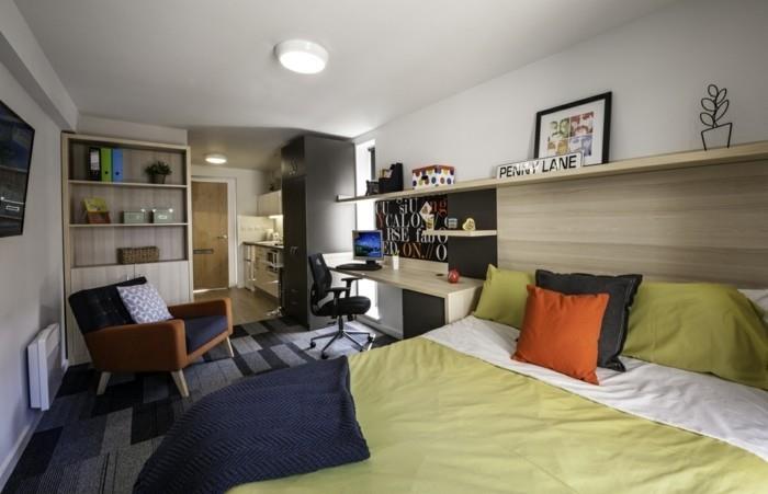 küçük-alan-geniş-yatak-yeşil-battaniye-rahat-sandalye-yastıklar-masa