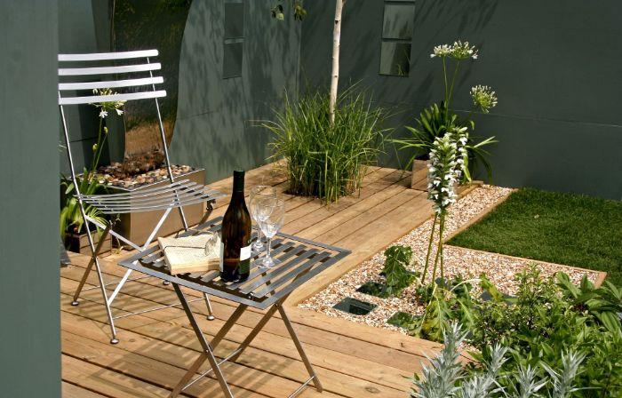 opremite svojo leseno teraso s stolom in kovinsko namizno gramozno obrobo zeleno travo šimšir druge zelene rastline