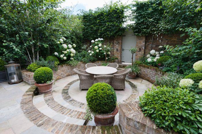 razviti svojo zunanjo teraso s ploščami in kamnitim vrtnim pohištvom iz ratana ter okroglo mizo okoli zelenih rastlin in pušpana