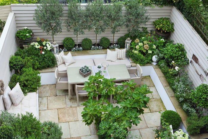 razviti zunanjo teraso v kamnitih ploščah vrtno pohištvo, obdano z zelenim rastlinjem šimširom in drevesi