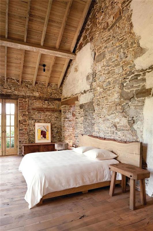 miegamasis seno namo palėpėje su atviromis akmeninėmis sienomis ir medinėmis karkasinėmis grindimis bei lova