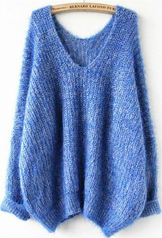 Devintojo dešimtmečio mados moteris atrodo su dideliu megztiniu, mėlynos spalvos ir didele iškirpte