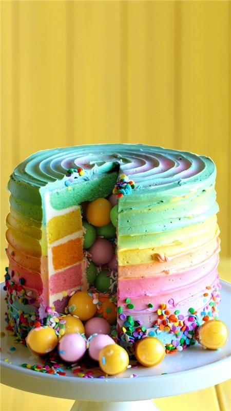 kako narediti izvirno torto presenečenja v barvah mavrice, mavrično torto s kokosom in večbarvno glazuro s sladkarijami in sladkornimi posipi v notranjosti