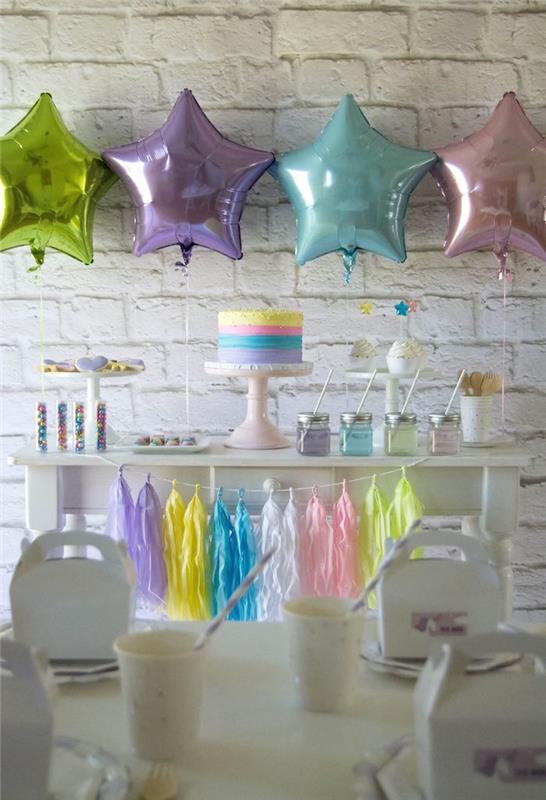 sladkarija v pastelnih tonih, okrašena z baloni iz folije v obliki zvezd, vencem iz resic in enorogovo torto z mavrično glazuro