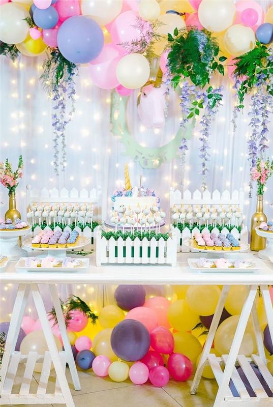 kmečki rojstnodnevni bife v duhu vrtne zabave z lokom iz balona, ​​cvetličnimi venci in kartonskim predmetom za enoroga