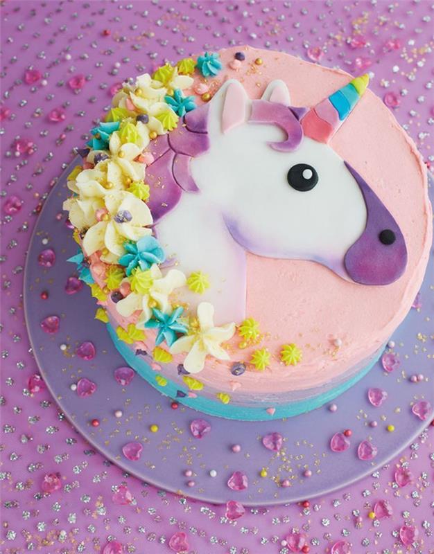 originalus vaivorykštės tortas, skirtas gimtadieniui švęsti vienaragio tema, gražus vaivorykštinis tortas su pastelinėmis spalvomis dekoruotu glajumi, dekoruotas vienaragio galva cukraus pasta ir gėlėmis glazūroje