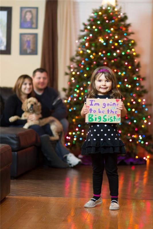 Noel ağacının yanında bir aile, senaryolu bir karatahta ile gelecekteki kız kardeş