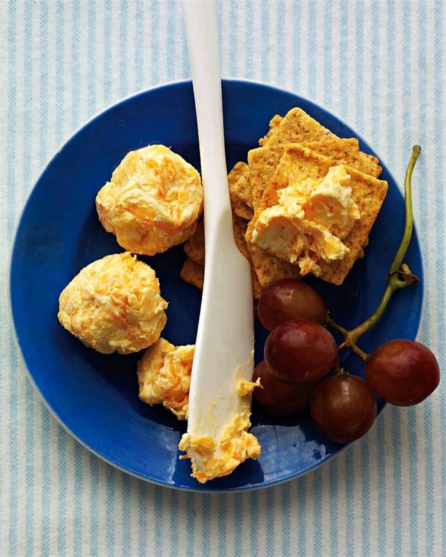 ideja za aperitiv na hladno večerjo, narejen s sirom, cheddarjevimi kroglicami in naribanim korenjem, ki ga spremljajo rozine in krekerji