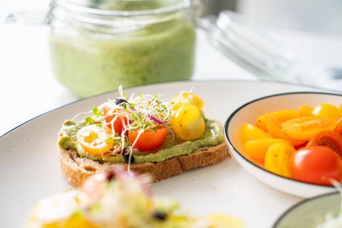 ideja, kako narediti pesto iz bazilike kot aperitiv za hladno večerjo z avokadom, toastom, okrašenim s češnjevimi paradižniki, kalčkami