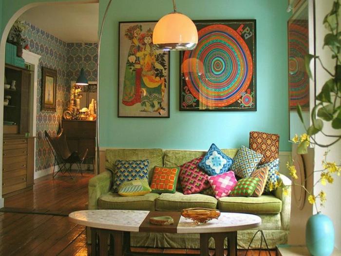ovalna bela tabla, zelen kavč, okvirjene slike, viseča stropna svetilka, viseča rastlina, lesena tla