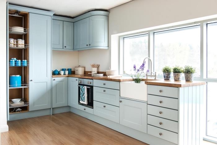 dekor v vintage slogu v beli kuhinji s pohištvom iz pastelno modre barve in pultom iz surovega lesa