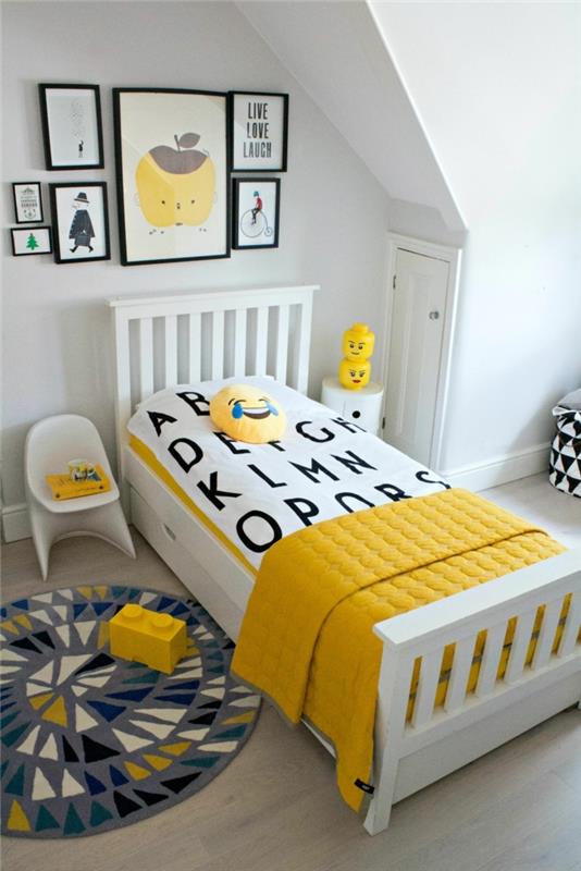 pilkas kilimas, geltoni „Lego“ elementai, balta kėdė, abstrakčių paveikslų rėmai
